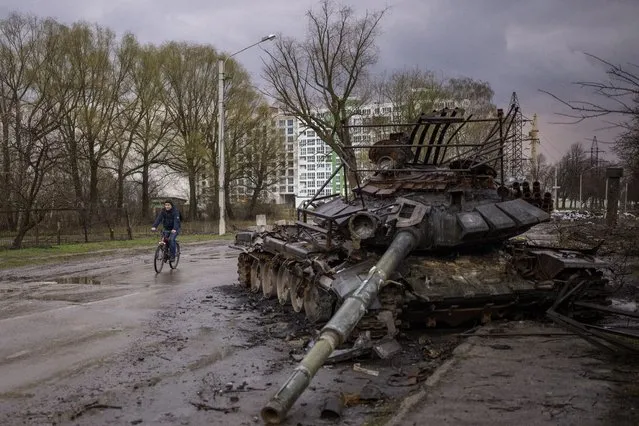 A man rides his bicycle next to a destroyed Russian tank in Chernihiv, Ukraine, on Thursday, April 21, 2022. (Photo by Emilio Morenatti/AP Photo)