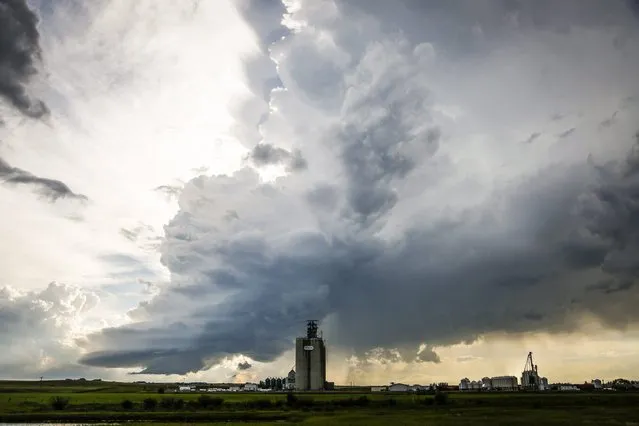 Storm clouds gather over a grain elevator near Carstairs, Alberta, Tuesday, July 21, 2015. (Photo by Jeff McIntosh/The Canadian Press via AP Photo)