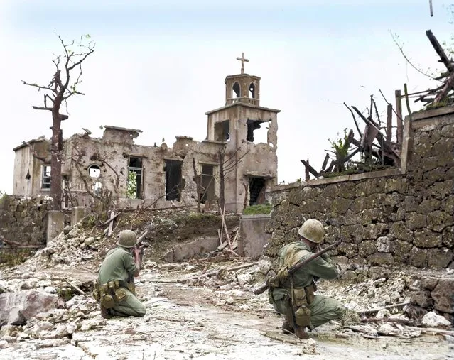 While a patrol moves in from the rear, two United States Marines cover a Japanese sniper hiding in a church, below Shuri Castle on Okinawa, 1945. (Photo by Royston Leonard/Mediadrumworld)