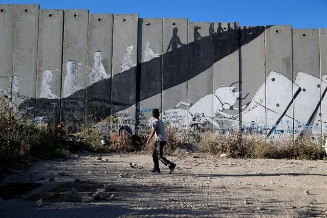 A Palestinian boy walks past graffiti painted on the controversial Israeli barrier in the West Bank town of Bethlehem, April 27, 2016. (Photo by Ammar Awad/Reuters)