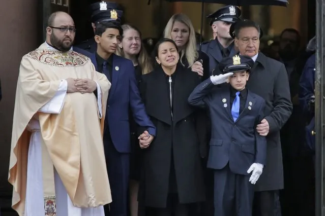 Mourners of Jersey City Police Detective Joseph Seals, including his wife Laura Seals, center, watch as his casket is carried out of the church in Jersey City, N.J., Tuesday, December 17, 2019. The 40-year-old married father of five was killed in a confrontation a week ago with two attackers who then drove to a kosher market and killed three people inside before dying in a lengthy shootout with police. (Photo by Seth Wenig/AP Photo)