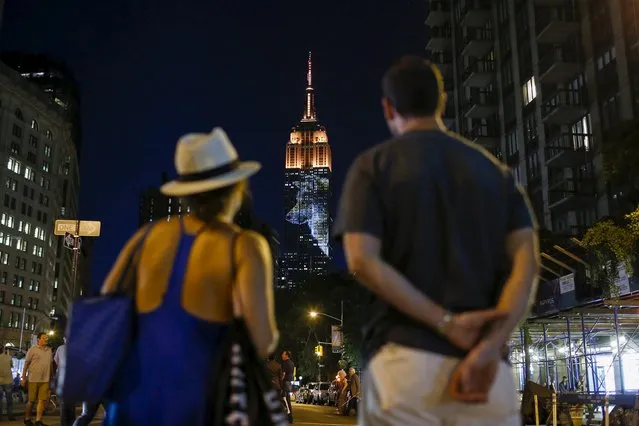 People watch as an image of an animal is projected onto the Empire State Building as part of an endangered species projection to raise awareness, in New York August 1, 2015. (Photo by Eduardo Munoz/Reuters)