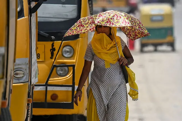 A woman uses an umbrella during a hot afternoon in New Delhi on May 15, 2022. (Photo by Money Sharma/AFP Photo)