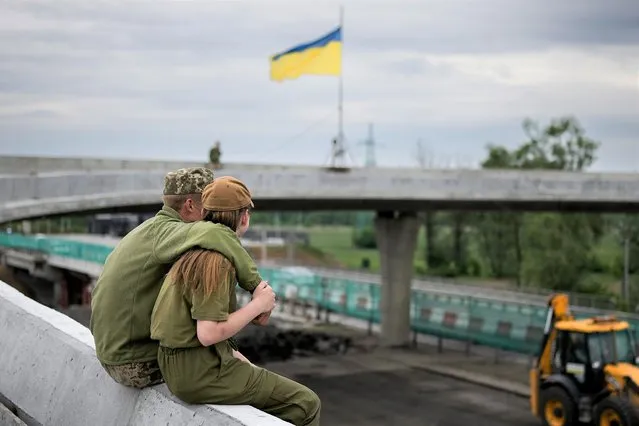 Two Ukrainian soldiers enjoy a tender off-duty moment near the village of Stoyanka on May 30, 2022 in Kyiv, Ukraine. As Russia concentrates its attack on the east and south of the country, residents of the Kyiv region are returning to assess the war's toll on their communities. The towns around the capital were heavily damaged following weeks of brutal war as Russia made its failed bid to take Kyiv. (Photo by Christopher Furlong/Getty Images)