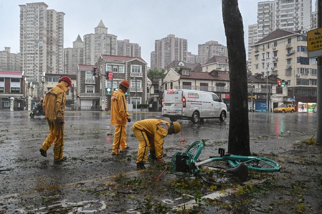 Workers clear debris from roads amid strong winds and rain from the passage of Typhoon Bebinca in Shanghai on September 16, 2024. (Photo by Hector Retamal/AFP)