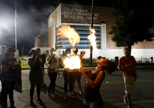 Laura Charles performs with fire sticks during a protest outside the police department in Ferguson, Missouri August 8, 2015. (Photo by Rick Wilking/Reuters)