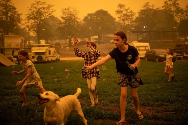 Children play at the showgrounds in the southern New South Wales town of Bega where they are camping after being evacuated from nearby sites affected by bushfires on December 31, 2019. Thousands of holidaymakers and locals were forced to flee to beaches in fire-ravaged southeast Australia on December 31, as blazes ripped through popular tourist areas leaving no escape by land. (Photo by Sean Davey/AFP Photo)