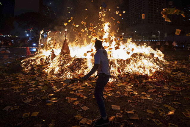 Ethnic Chinese throw paper offerings during the burning of a giant paper statue of the Chinese deity “Da Shi Ye” or “Guardian God of Ghosts” as it burns during the Chinese Hungry Ghost Festival in Kuala Lumpur, Monday, August 19, 2024. (Photo by Vincent Thian/AP Photo)