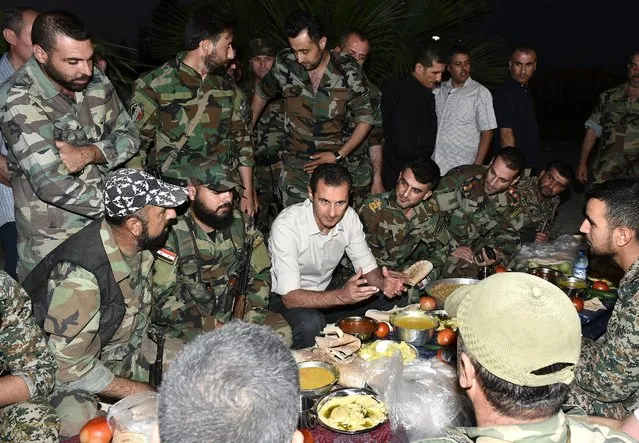 Syria's president Bashar al-Assad (C) joins Syrian army soldiers for Iftar in the farms of Marj al-Sultan village, eastern Ghouta in Damascus, Syria in this handout picture provided by SANA on June 26, 2016. (Photo by Reuters/SANA)