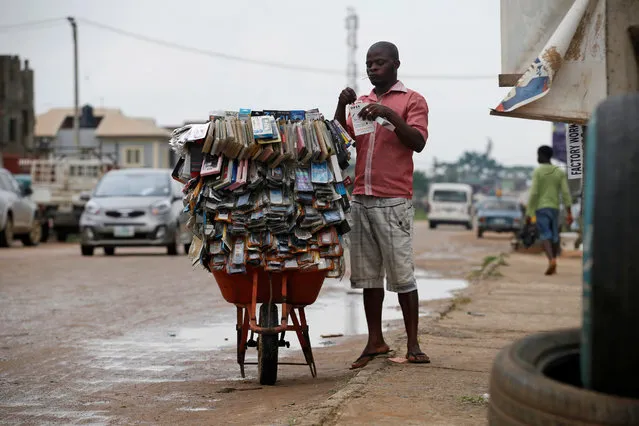 A man selling phone pouches on a wheelbarrow stands along a road in Ojodu district in Nigeria's commercial capital Lagos June 21, 2016. (Photo by Akintunde Akinleye/Reuters)
