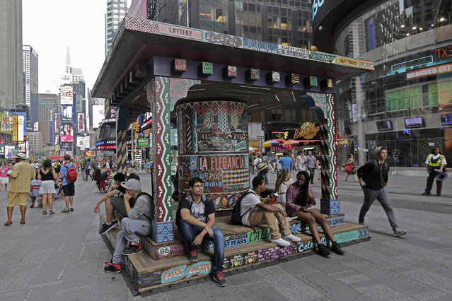 A large-scale art installation titled “Wishing on You”, an interactive work by the Brooklyn-based artists Patrick McNeil and Patrick Miller known as FAILE, has been placed in New York's Times Square, Monday, August 17, 2015. The public can spin a hand-carved wheel to power the sculpture's red-blue-and-white lights and illuminate carnival-like features including nickel arcades and glossy ads. (Photo by Richard Drew/AP Photo)