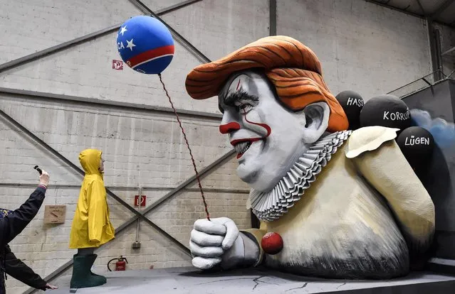 A man takes a picture of a satiric carnival float depicting US President Donald Trump as horror clown Pennywise during a preview in a hall in Cologne, Germany, Tuesday, February 18, 2020. The traditional carnival parades on Rosemonday make fun of politics and are watched by hundreds of thousands in the streets of Cologne, Duesseldorf and Mainz. (Photo by Martin Meissner/AP Photo)