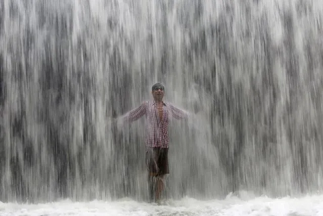 A boy stands under an overflowing dam along the Powai lake after heavy rains in Mumbai, India, July 4, 2016. (Photo by Shailesh Andrade/Reuters)