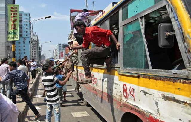 Bangladeshi passengers jump out of the windows of a bus that was attacked during clashes between garment workers and police in Dhaka, Bangladesh, Thursday, August 7, 2014. Bangladesh police on Thursday entered the premises of a garment factory, fired tear gas and used batons to disperse workers who were on a hunger strike since July 28 demanding payment of their salaries and festival allowances. (Photo by A. M. Ahad/AP Photo)