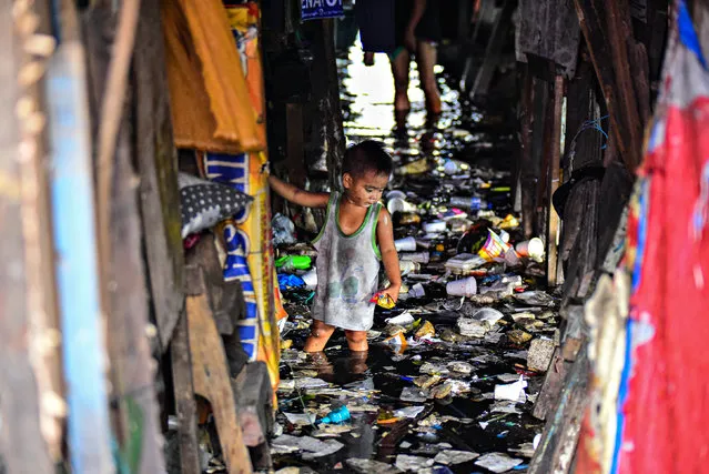 This photo taken on September 29, 2019 shows a child wading through the trash filled and polluted waters of a river beside their home in Manila. (Photo by Maria Tan/AFP Photo)