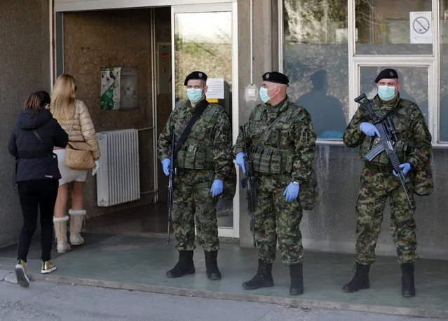 Serbian Army soldiers guard the Clinic for Infectious and Tropical Diseases in Belgrade, Serbia, Monday, March 16, 2020. Serbia's army troops are being deployed to the country's borders and streets of the capital, Belgrade, to reinforce a nationwide state of emergency that has been introduced in an effort to try stop the coronavirus outbreak. For most people, the new coronavirus causes only mild or moderate symptoms, such as fever and cough. For some, especially older adults and people with existing health problems, it can cause more severe illness, including pneumonia. (Photo by Darko Vojinovic/AP Photo)