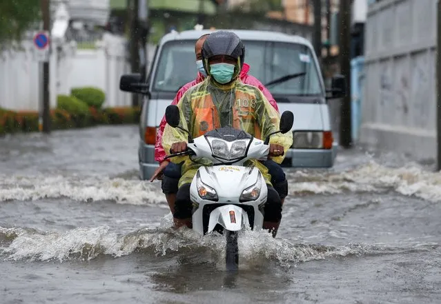 A man drives his motor bike on a flooded road after heavy rain fall during the high tide time in Bangkok, Thailand on July 21, 2022. (Photo by Soe Zeya Tun/Reuters)