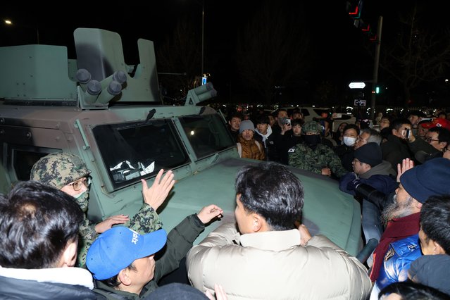 People surround a military vehicle outside the National Assembly in Seoul after South Korean President Yoon Suk Yeol declared martial law in Seoul, South Korea, early 04 December 2024. South Korean President Yoon Suk Yeol had declared martial law on 03 December night, citing the need to root out pro-North Korean forces and uphold the constitutional order. (Photo by Han Myung-Gu/EPA/EFE)