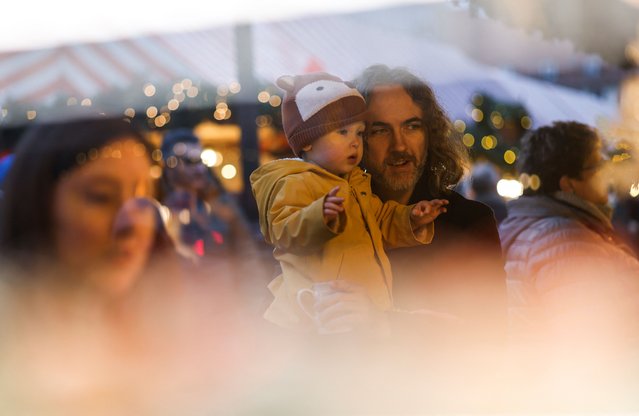 A man holds a baby, at the famous “Nuernberger Christkindlesmarkt” (Christ Child Market), one of the world's oldest Christmas markets, on the day of its opening ceremony, in Nuremberg, Germany, on November 29, 2024. (Photo by Michaela Stache/Reuters)