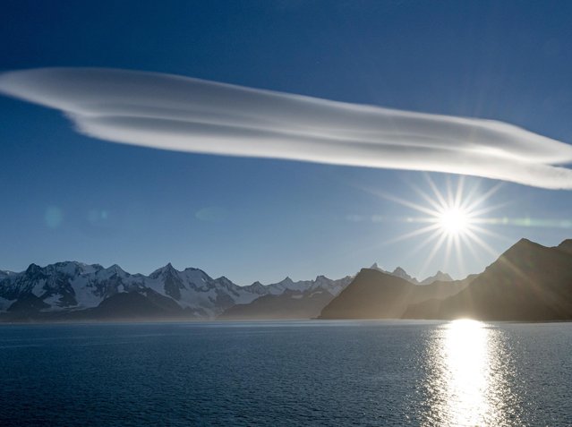 Lenticular clouds hang over South Georgia, part of a British Overseas Territory 1,000 miles east of the Falklands in May 2022. Often confused for UFOs, they form when a wave of air rises to meet moist air on the leeward side of a mountain. (Photo by Shane Gross/Naturepl/Solent News)