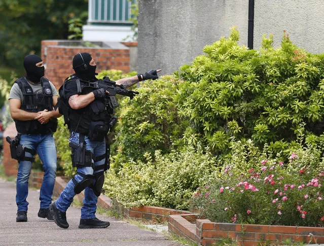 Hooded Police officers conduct a search in Saint-Etienne-du-Rouvray, Normandy, France, following an attack on a church that left a priest dead, Tuesday, July 26, 2016. Two attackers invaded a church Tuesday during morning Mass near the Normandy city of Rouen, killing an 84-year-old priest by slitting his throat and taking hostages before being shot and killed by police, French officials said. (Photo by Francois Mori/AP Photo)