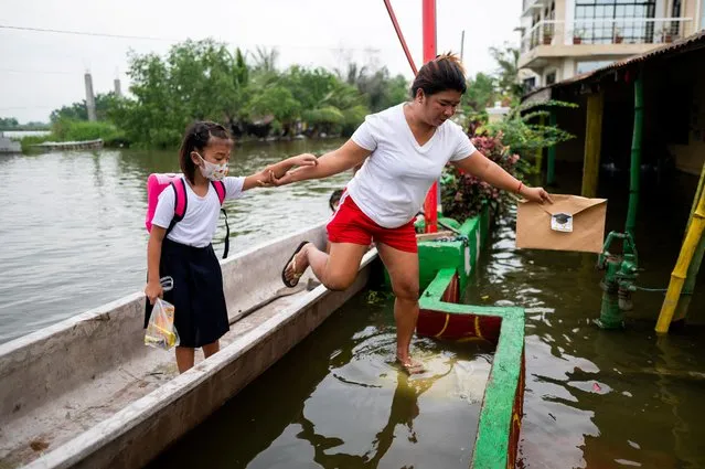A woman and a child arrive at a flooded school due to high tide, during the first day of in-person classes, in Macabebe, Pampanga province, Philippines, August 22, 2022. (Photo by Lisa Marie David/Reuters)