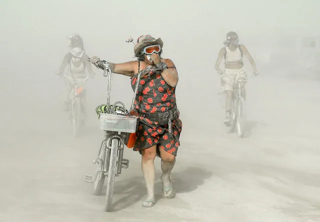 Participants make their way through dust at Burning Man in the Black Rock Desert of Nevada on Wednesday, September 2, 2015. The 29th annual alternative living event is traditionally centered around the ritual burning of a large wooden effigy. (Photo by Andy Barron/The Reno Gazette-Journal via AP Photo)