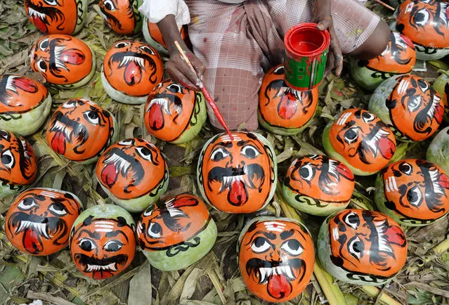 An Indian vendor paints pumpkins to resemble demons at a wholesale market during the Durga Puja festival in Chennai on September 28, 2017. Devotees believe that smashing pumpkins painted with demon faces drives away evil spirits. The five- day Durga Puja festival, which commemorates the slaying of the demon king Mahishasur by the goddess Durga, marks the triumph of good over evil. (Photo by Arun Sankar/AFP Photo)
