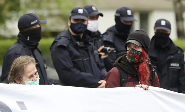 Protesters wearing face masks to protect against the coronavirus, gather before the start of parliament in Warsaw, Poland, on Wednesday, May 6, 2020. Parliament needs to decide whether the postal presidential election is to be postponed from Sunday until May 23. The ruling party wants the election in May, the Senate is calling for a state of natural disaster that would allow for postponement by three months. (Photo by Czarek Sokolowski/AP Photo)