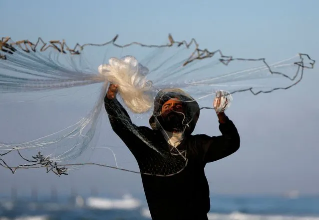 A Palestinian fisherman throws his net on the beach as he prepares it for fishing in Khan Younis in the southern Gaza Strip on September 11, 2022. (Photo by Ibraheem Abu Mustafa/Reuters)