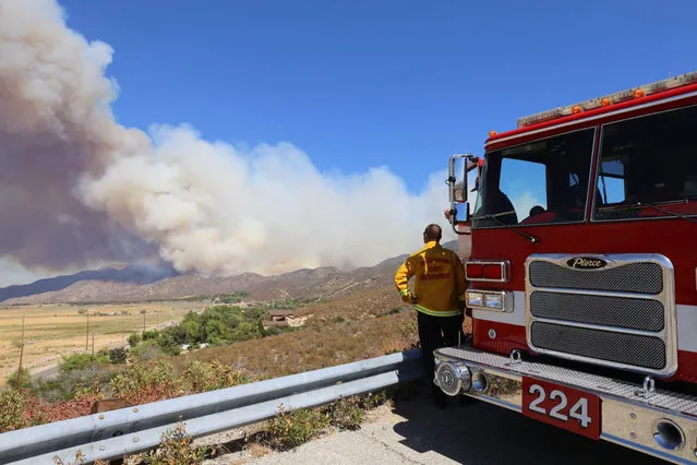 A San Bernardino County Fire Department engine and its crew keep watch over Summit Valley, Calif., as a wildfire burns east of Silverwood Lake on Sunday, August 7, 2016. Firefighters are battling a wildfire in Southern California that grew to more than 2 square miles in mere hours and forced the evacuation of homes near a reservoir. The fire, which broke out Sunday afternoon in the San Bernardino National Forest, prompted the evacuation order of the sparsely populated Summit Valley area east of the dam. (Photo by John M. Blodgett/The Inland Valley Daily Bulletin via AP Photo)