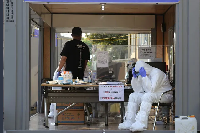A health official wearing protective gear takes a rest during the COVID-19 testing at a public health center in Goyang, South Korea, Thursday, May 28, 2020. South Korea on Thursday reported its biggest jump in coronavirus cases in more than 50 days, a setback that could erase some of the hard-won gains that have made it a model for the rest of the world. (Photo by Ahn Young-joon/AP Photo)