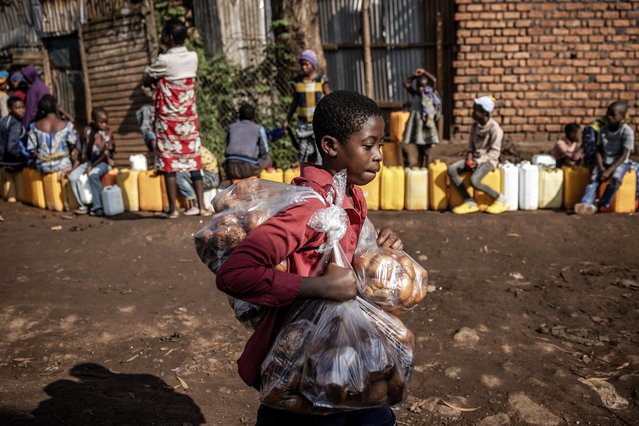A boy sells snacks as residents queue with their water jars to collect water from a water point in Bukavu on February 21, 2025. Congolese President Felix Tshisekedi is on a quest for support as war in the east rages, but has so far returned empty-handed from trips abroad while anxiety mounts at home. Tshisekedi recently visited Angola and attended a security conference in Munich without making a clear diplomatic breakthrough, after Rwanda-backed M23 fighters seized control of two major eastern cities in the Democratic Republic of Congo. (Photo by Luis Tato/AFP Photo)