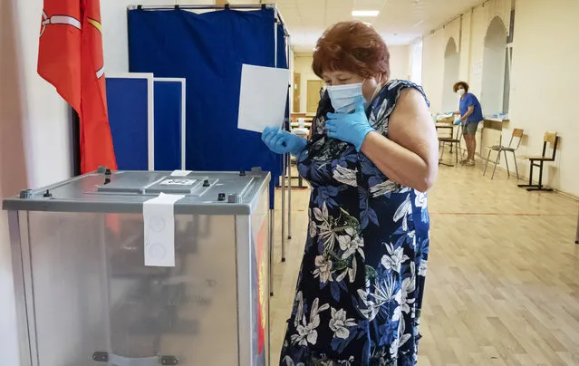 A voter wearing a face mask and protective gloves to protect against coronavirus walks to cast her ballot at a polling station in St.Petersburg, Russia, Thursday, June 25, 2020. Polls have opened in Russia on Thursday for a week-long vote on a constitutional reform that may allow President Vladimir Putin to stay in power until 2036. (Photo by Dmitri Lovetsky/AP Photo)
