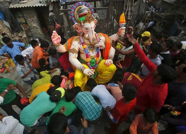 Devotees prepare to load an idol of the Hindu god Ganesh, the deity of prosperity, onto a truck to a place of worship on the first day of the ten-day-long Ganesh Chaturthi festival in New Delhi, India, September 17, 2015. (Photo by Anindito Mukherjee/Reuters)