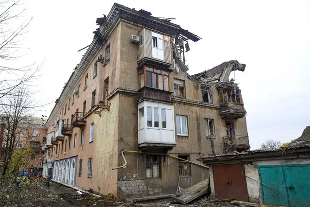 Rescuers, left, work at a site of a damaged apartment building after shelling by Ukrainian forces in Makiivka, Donetsk People's Republic, eastern Ukraine, Friday, November 4, 2022. (Photo by AP Photo/Stringer)