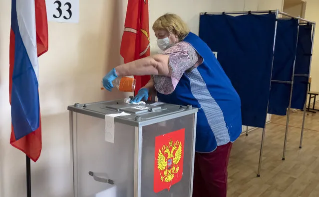 A polling station employee wearing a face mask and gloves to protect against coronavirus disinfects a ballot box at a polling station in St.Petersburg, Russia, Thursday, June 25, 2020. Polls have opened in Russia on Thursday for a week-long vote on a constitutional reform that may allow President Vladimir Putin to stay in power until 2036. (Photo by Dmitri Lovetsky/AP Photo)