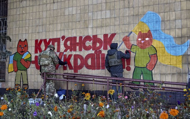 A group of Ukrainian artists draws graffiti on a wall reading “Kupiansk is Ukraine” in the recently recaptured city of Kupiansk, east of Kharkiv, northeastern Ukraine, 16 October 2022. The Ukrainian army pushed Russian troops from occupied territory in the northeast of the country in counterattacks. Kharkiv and surrounding areas have been the target of heavy shelling since February 2022, when Russian troops entered Ukraine starting a conflict that has provoked destruction and a humanitarian crisis. (Photo by Sergey Kozlov/EPA/EFE)