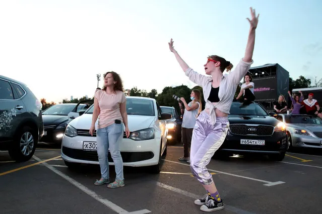 People dance outside their cars during a drive-in concert by The Hatters gypsy folk rock band in Luzhniki, Moscow, Russia on July 4, 2020. The concert, in which the sound is broadcast to the cars via FM radio, is part of LIVE&DRIVE, a series of live drive-in concerts organised by the TCI concert agency and SAV Entertainment Group during the pandemic of the novel coronavirus disease (COVID-19). (Photo by Vyacheslav Prokofyev/TASS)