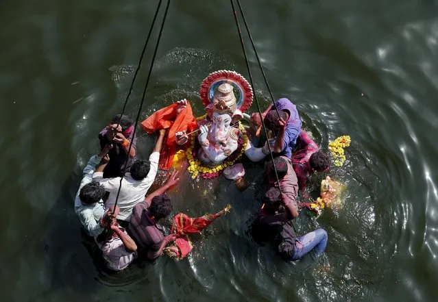 Devotees immerse an idol of the Hindu god Ganesh, the deity of prosperity, into the Sabarmati river on the last day of the 10-day-long Ganesh Chaturthi festival in Ahmedabad, India, September 27, 2015. (Photo by Amit Dave/Reuters)