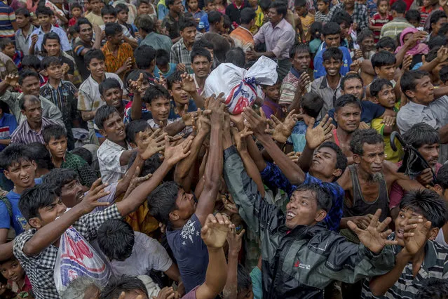 Rohingya Muslims, who crossed over from Myanmar into Bangladesh, stretch their arms out to collect food items distributed by aid agencies near Balukhali refugee camp, Bangladesh, on September 18, 2017. (Photo by Dar Yasin/AP Photo)
