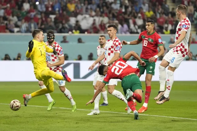 Morocco's Achraf Dari, center, scores his side's first goal as Croatia's goalkeeper Dominik Livakovic, left, fails to defend during the World Cup third-place playoff soccer match between Croatia and Morocco at Khalifa International Stadium in Doha, Qatar, Saturday, December 17, 2022. (Photo by Andre Penner/AP Photo)