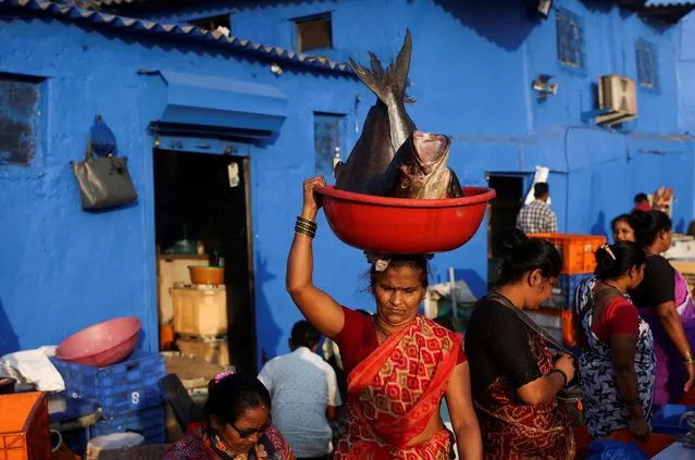 A woman carries fish in a tub, at a fish market in Mumbai, India on December 28, 2022. (Photo by Francis Mascarenhas/Reuters)