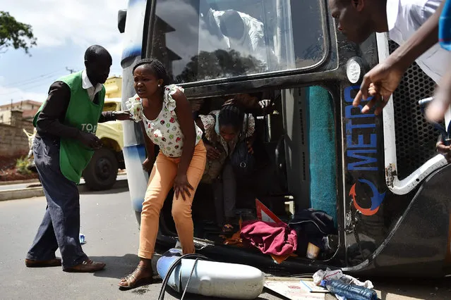 An injured passenger walks out the wreckage of a bus that tipped onto its side following a collision with a lorry in Nairobi on January 12, 2018. A speeding lorry ferrying soil crashed into the side of the bus on the intersection of James Gichuru and Gitanga road in the capital Nairobi's Lavington suburb leaving the bus on its side and passengers with flesh wounds. (Photo by Tony Karumba/AFP Photo)