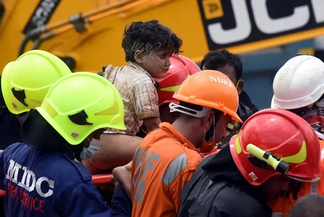 Rescue workers carry Mohammed Bangi, a four-year-old boy, as he leaves a hospital after he was rescued from the rubble at the site of a collapsed five-storey building in Mahad in Raigad district in the western state of Maharashtra, India, August 25, 2020. (Photo by Reuters/Stringer)