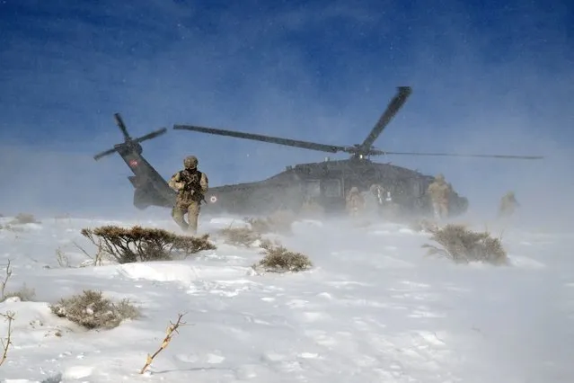 A commando of the Van Provincial Gendarmerie Command is seen with his gun as a military helicopter is seen behind in snow covered terrain in Van, Turkiye on December 24, 2022. Van Provincial Gendarmerie Command teams, which carried out successful operations against the PKK, listed as a terrorist organization by Turkiye, US and EU, and smugglers, found over 150 shelters last year, seized many weapons, thousands of cartridges, and large amounts of life supplies. Gendarmerie teams, working 24 hours a day, 7 days a week in the fight against terrorism, prevention of illegal migration, fight against irregular migration, prevention of drugs and smuggling, catching criminals, are making efforts for the peace and security of the region by using all the means of technology. Gendarmerie teams, who do not interrupt their duties on high hills, deep valleys and rocky areas despite adverse weather conditions, use all kinds of technology. (Photo by Ozkan Bilgin/Anadolu Agency via Getty Images)