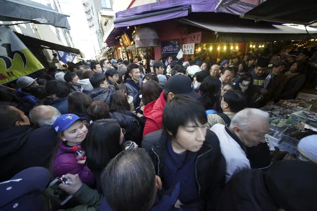 Streets are crowded by tourists and shoppers near Tsukiji fish market in Tokyo Friday, December 29, 2017. Tsukiji fish market is crowded by shoppers who look for ingredients for “osechi” or Japanese traditional New Year dishes. (Photo by Eugene Hoshiko/AP Photo)
