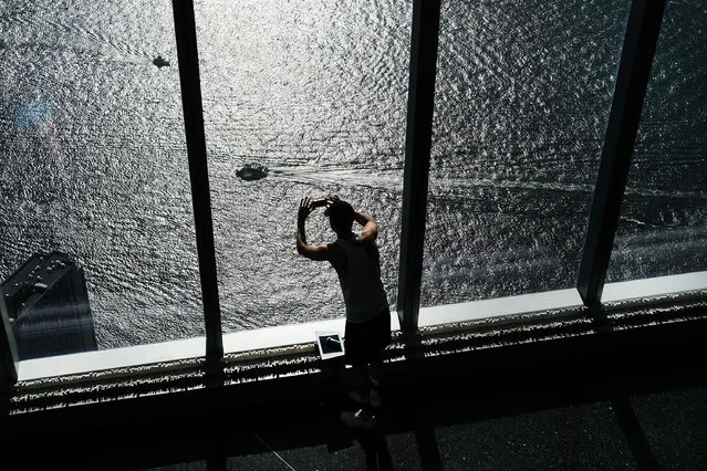 A man takes a photo of the Hudson River from the One World Observatory at One World Trade Center on August 22, 2016 in New York City.The observation deck sits atop the 104-story skyscraper at the former site of the former Twin Towers and is one of Manhattan's top tourist attractions. People are preparing to commemorate the 15th anniversary of the attacks on September 11, 2001. (Photo by Spencer Platt/Getty Images)