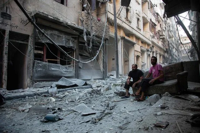 Syrians sit and look at the rubble following an airstrike on the regime-controlled neighbourdhood of Karm al-Jabal on September 18, 2016. Syria's ceasefire was on the brink of collapsing Sunday, after a US-led coalition strike killed dozens of regime soldiers and Aleppo city was hit by its first raids in nearly a week. (Photo by Karam Al-Masri/AFP Photo)