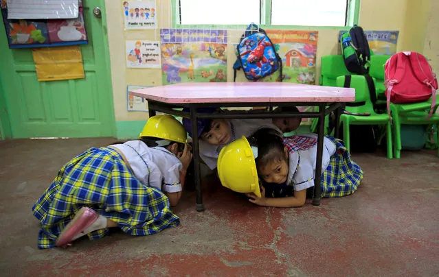 Students hide under the desk during simultaneous earthquake drills at an elementary school in Paranaque City, Metro Manila, Philippines February 15, 2018. (Photo by Romeo Ranoco/Reuters)
